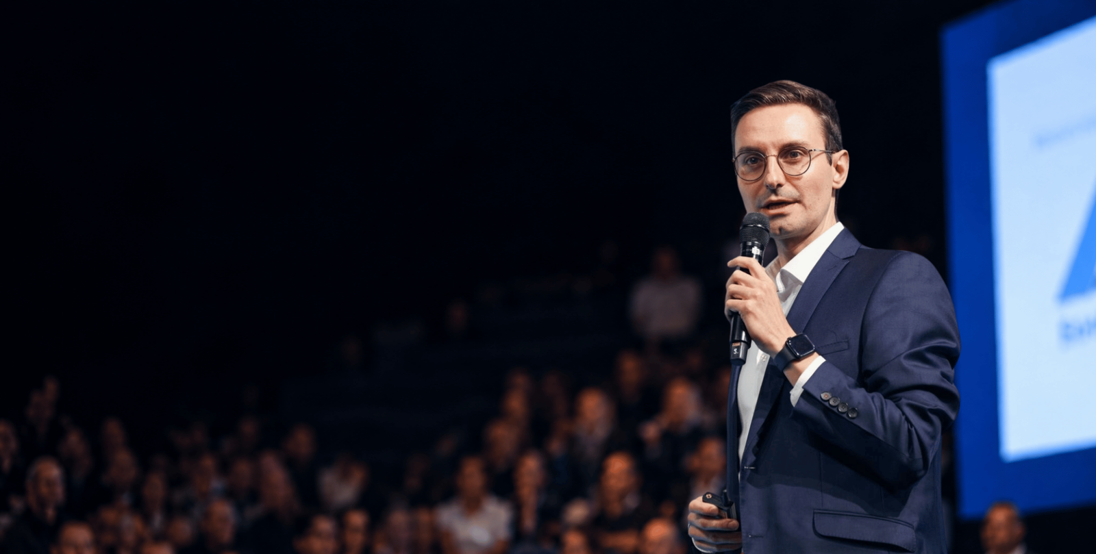 Gerald Zankl holding a microphone in front of a conference audience